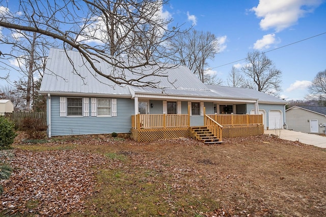 view of front of home featuring covered porch, metal roof, driveway, and an attached garage