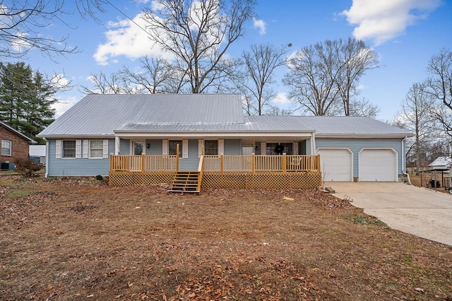 single story home with a porch, concrete driveway, metal roof, and an attached garage