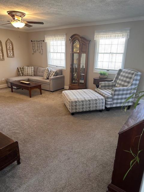 bedroom with a textured ceiling, a ceiling fan, crown molding, and light colored carpet