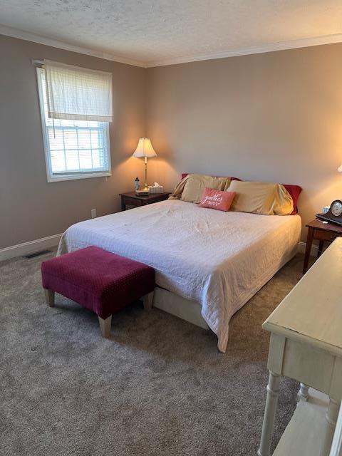 bedroom with a textured ceiling, ornamental molding, carpet, and baseboards