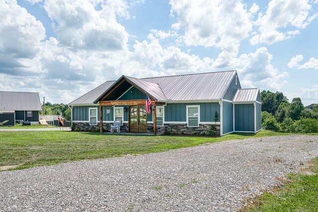 view of front of home with metal roof, stone siding, board and batten siding, and a front yard