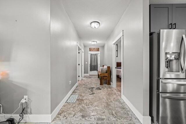 hall featuring baseboards and a textured ceiling