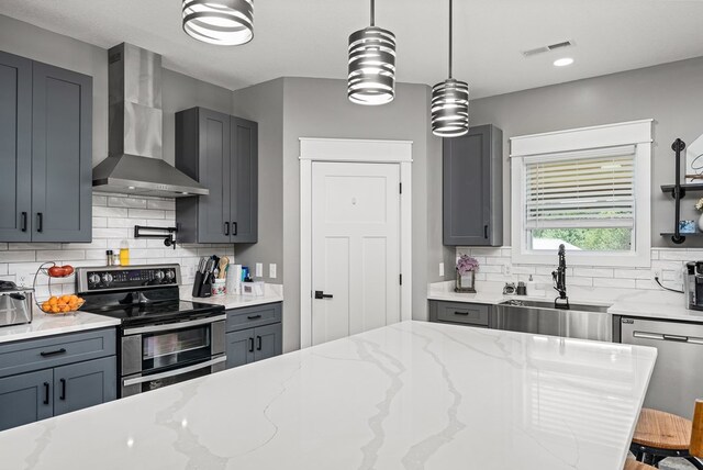 kitchen with wall chimney exhaust hood, light stone counters, a sink, and stainless steel appliances