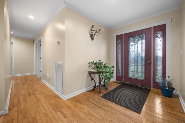 foyer entrance with light wood finished floors, visible vents, baseboards, and crown molding