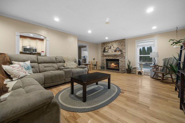 living area featuring crown molding, light wood-type flooring, a fireplace, and recessed lighting