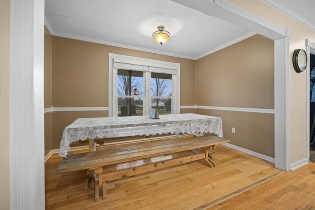 dining area with ornamental molding, wood finished floors, and baseboards