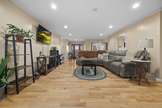 living area featuring arched walkways, crown molding, recessed lighting, light wood-type flooring, and baseboards