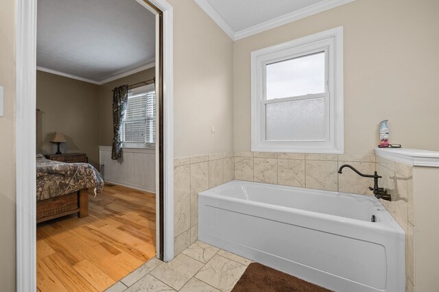 bathroom with connected bathroom, a wainscoted wall, ornamental molding, wood finished floors, and a bath