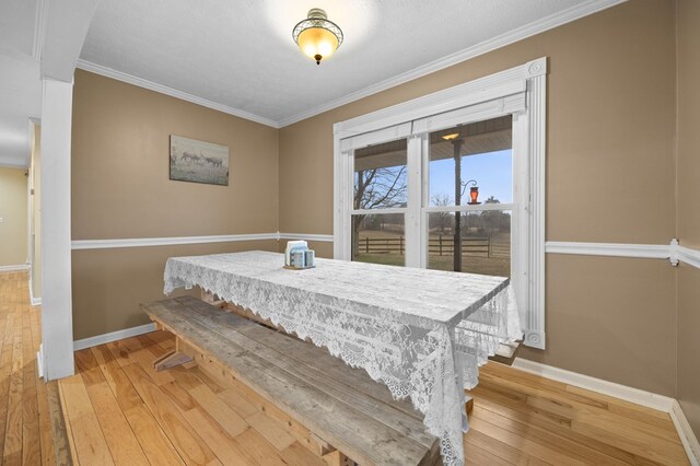 dining room featuring light wood-style flooring, baseboards, and crown molding