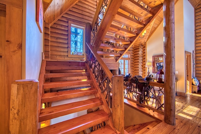 stairway with high vaulted ceiling, wood-type flooring, and baseboards