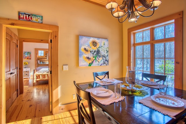 dining area featuring a chandelier, a wealth of natural light, light wood-style flooring, and baseboards