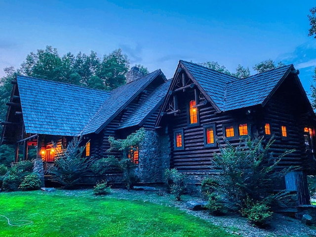 log home featuring log exterior, a chimney, and a front lawn