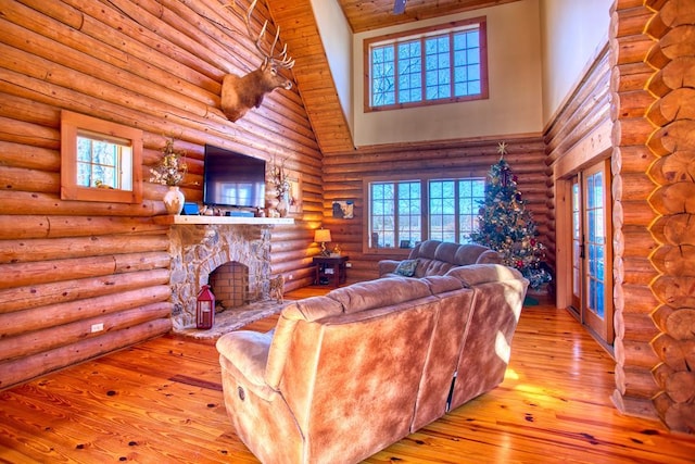 living area with rustic walls, a fireplace, hardwood / wood-style floors, and a towering ceiling