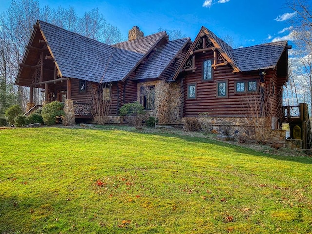 log-style house with stone siding, a front lawn, a chimney, and log siding