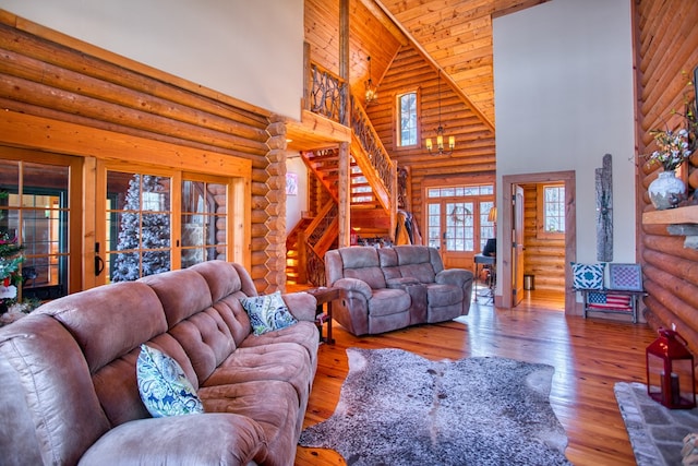 living area with high vaulted ceiling, wood-type flooring, rustic walls, and stairway