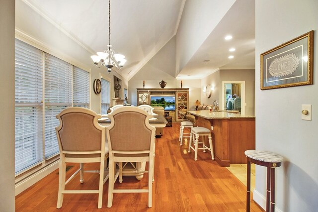 dining room featuring lofted ceiling, recessed lighting, ornamental molding, wood finished floors, and a chandelier