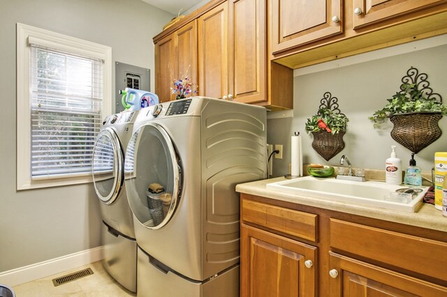 laundry area featuring washing machine and clothes dryer, cabinet space, visible vents, a sink, and baseboards