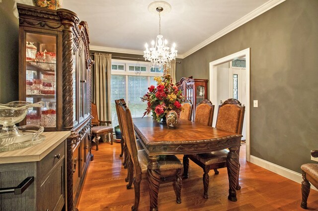 dining room with baseboards, a chandelier, crown molding, and wood finished floors