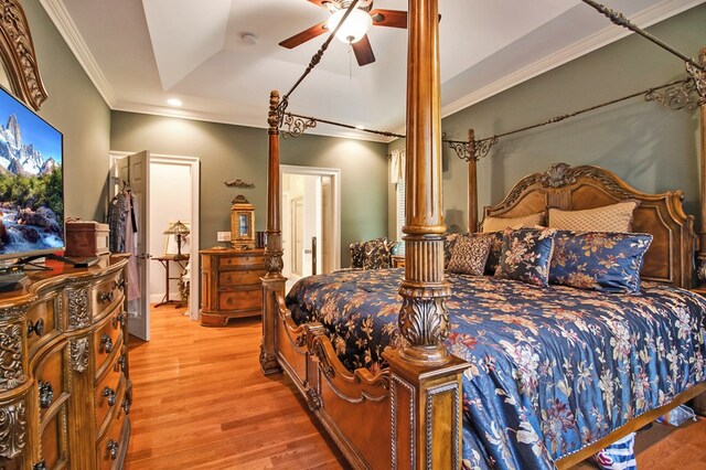 bedroom with ornamental molding, a tray ceiling, a ceiling fan, and wood finished floors