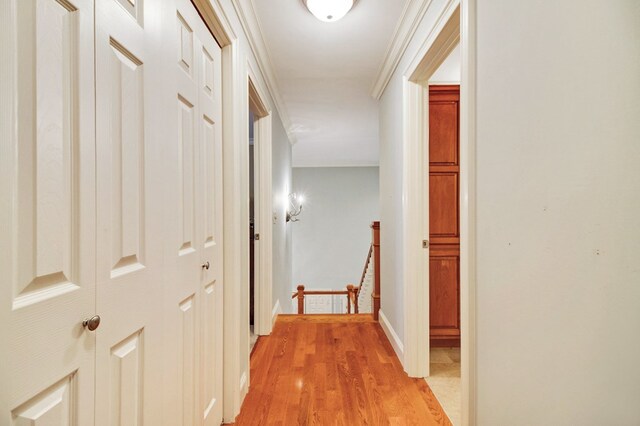 hall featuring baseboards, ornamental molding, an upstairs landing, and light wood-style floors