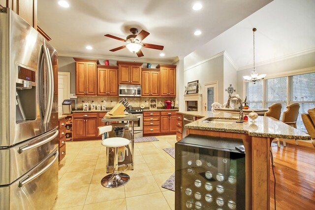 kitchen featuring a breakfast bar, stainless steel appliances, hanging light fixtures, and an island with sink