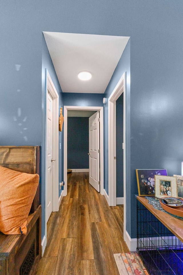 hallway with dark wood finished floors and baseboards