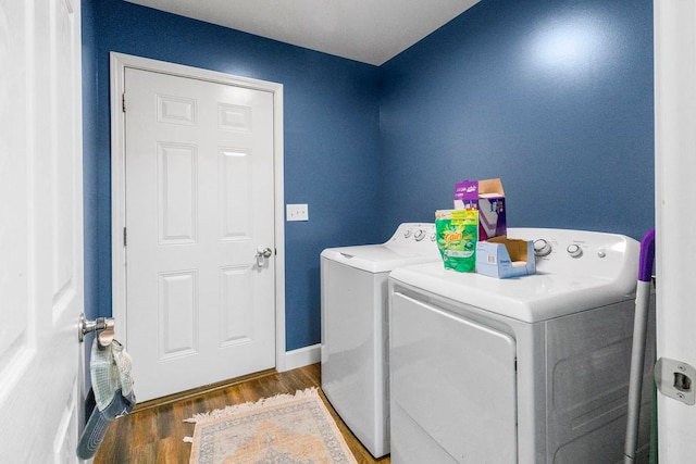 washroom featuring laundry area, baseboards, dark wood finished floors, and washing machine and clothes dryer