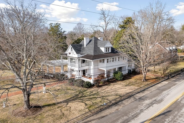 view of front of house featuring a chimney and a balcony