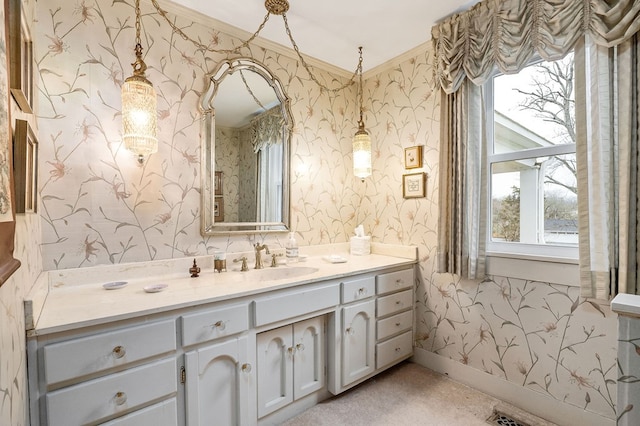 bathroom with wallpapered walls, baseboards, crown molding, and vanity