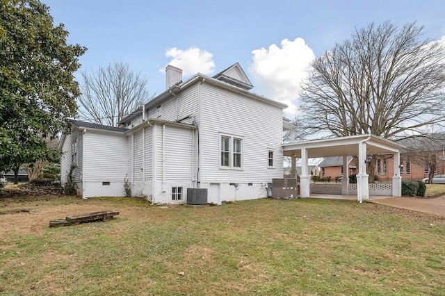 view of side of home featuring crawl space, driveway, a chimney, and a yard