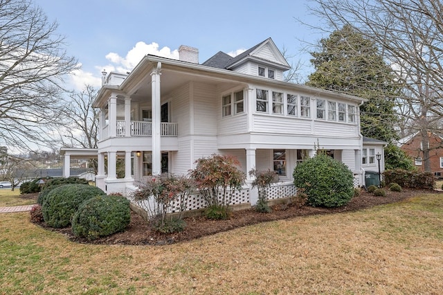 view of home's exterior featuring a chimney, a balcony, and a lawn