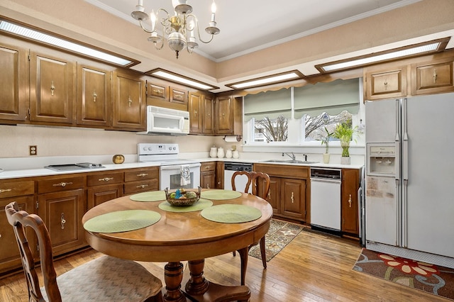 kitchen with white appliances, a sink, light countertops, ornamental molding, and brown cabinetry