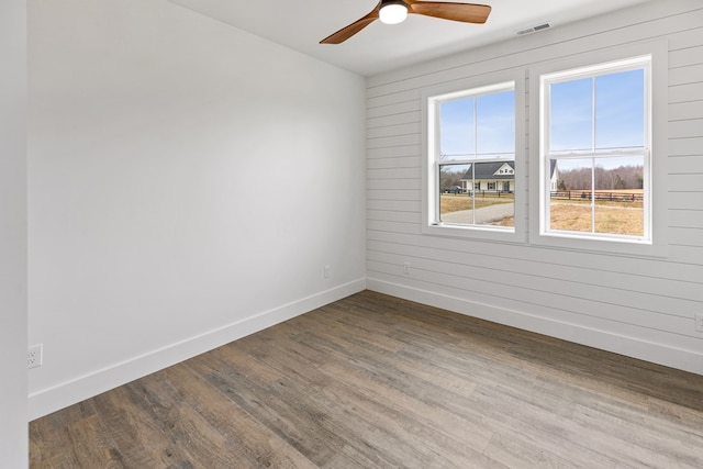 spare room with ceiling fan, wood finished floors, visible vents, and baseboards