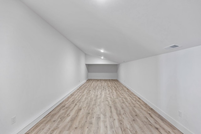 interior space featuring lofted ceiling, baseboards, visible vents, and light wood-style floors