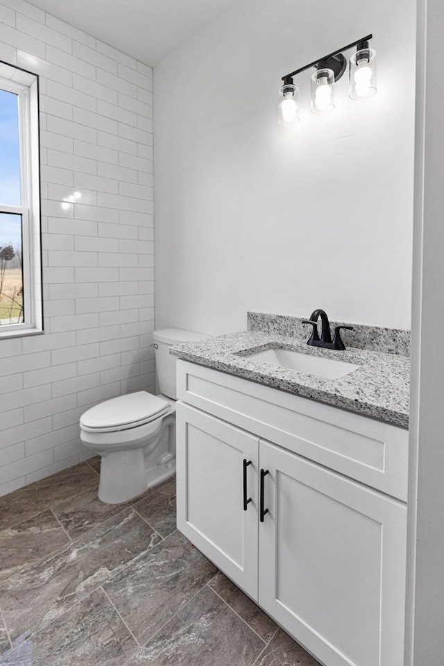 bathroom featuring toilet, tile walls, and vanity