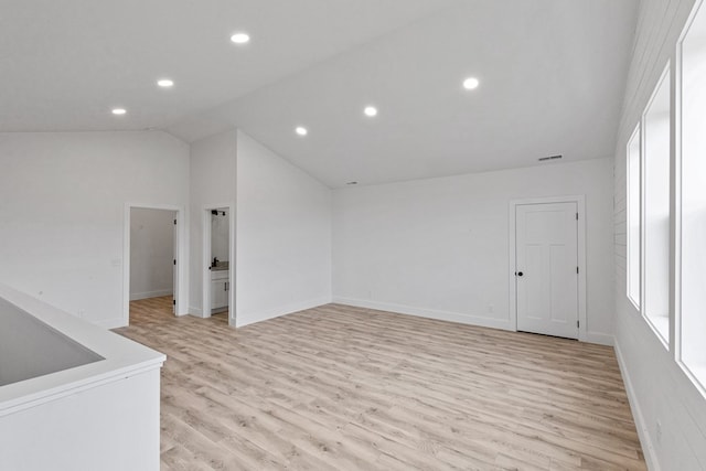 spare room with light wood-type flooring, baseboards, visible vents, and lofted ceiling