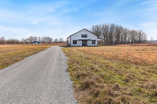 view of front of house with a front lawn, a rural view, and gravel driveway