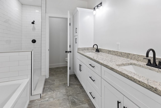 bathroom with double vanity, stone finish floor, a sink, and toilet