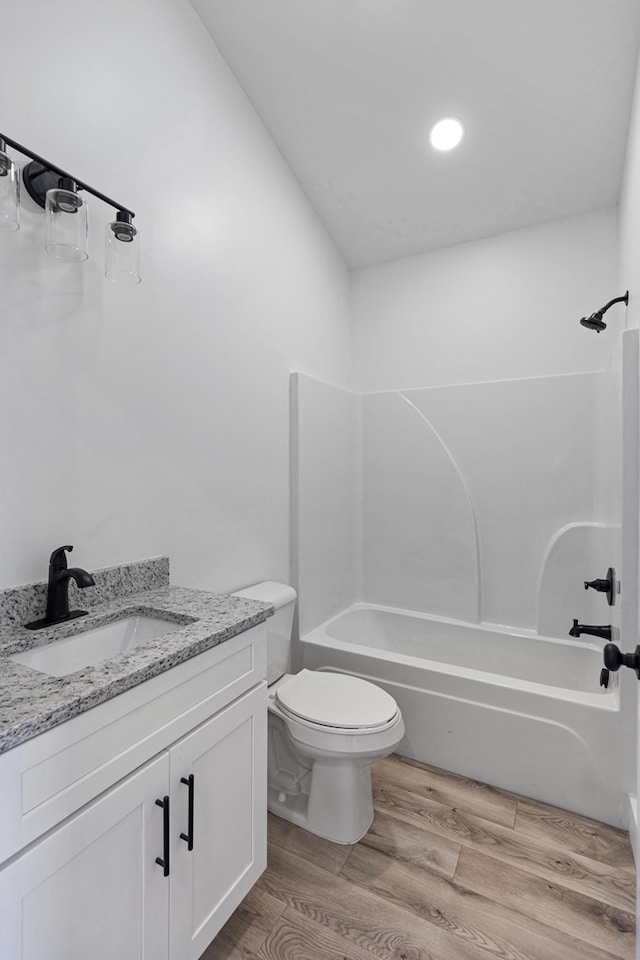 bathroom with  shower combination, vanity, toilet, and wood finished floors