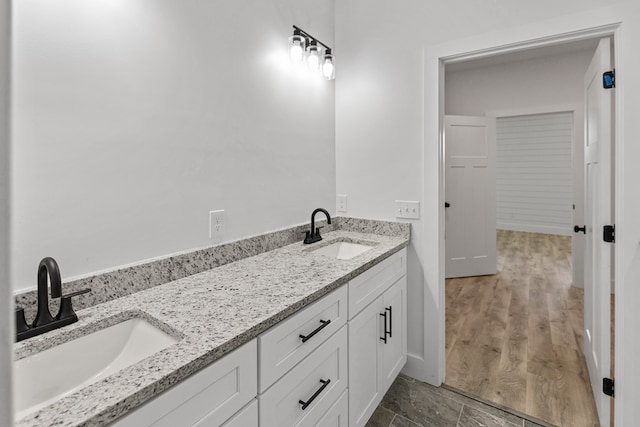 full bathroom with double vanity, a sink, and wood finished floors