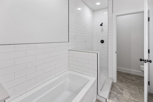 bathroom featuring baseboards, tiled shower, toilet, and a bath