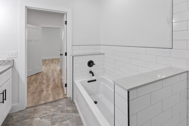 bathroom featuring a washtub, vanity, and stone tile floors