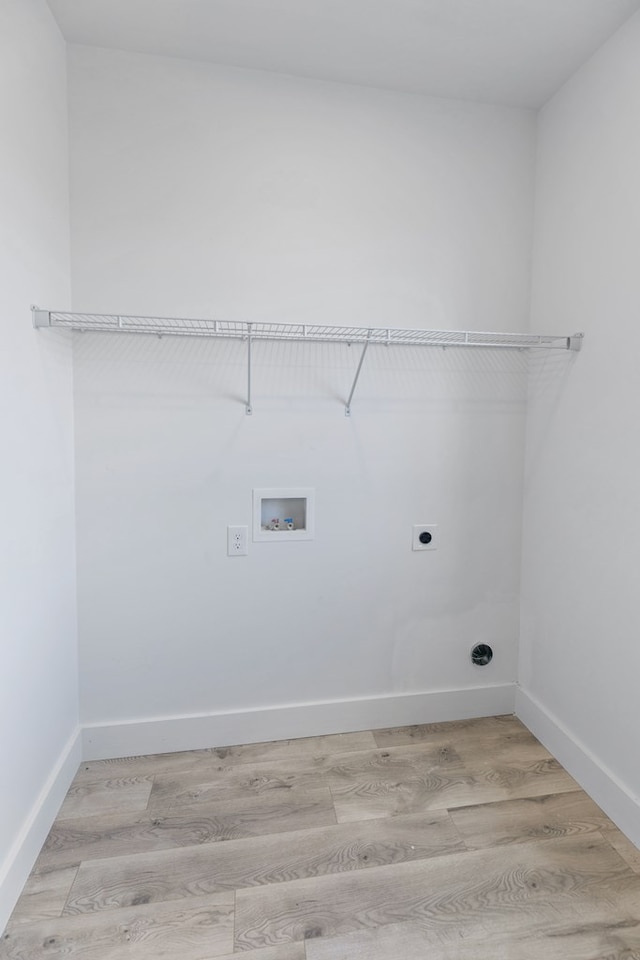 clothes washing area featuring laundry area, baseboards, light wood-style flooring, hookup for an electric dryer, and washer hookup