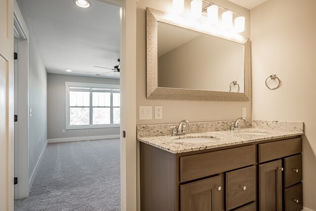 full bathroom featuring double vanity, baseboards, a ceiling fan, and a sink