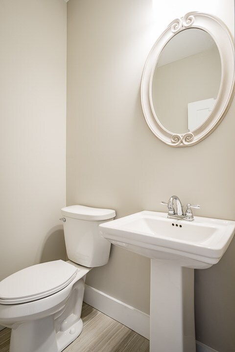 bathroom with a sink, toilet, baseboards, and wood finished floors