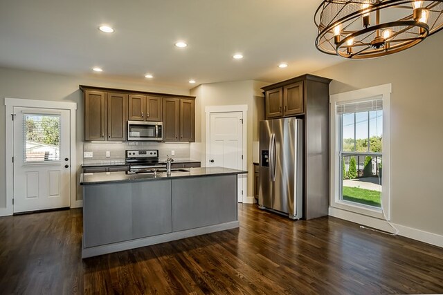 kitchen featuring dark countertops, appliances with stainless steel finishes, decorative backsplash, and dark wood finished floors