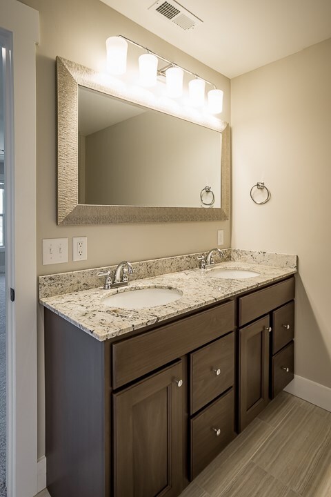 full bath with visible vents, a sink, baseboards, and double vanity