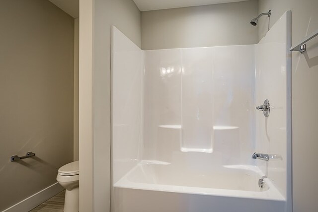 full bathroom with baseboards, tub / shower combination, toilet, and wood finished floors