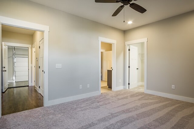 unfurnished bedroom featuring a closet, carpet flooring, a spacious closet, and baseboards