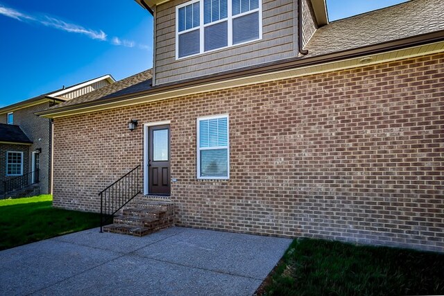 back of house featuring entry steps, brick siding, and a patio area